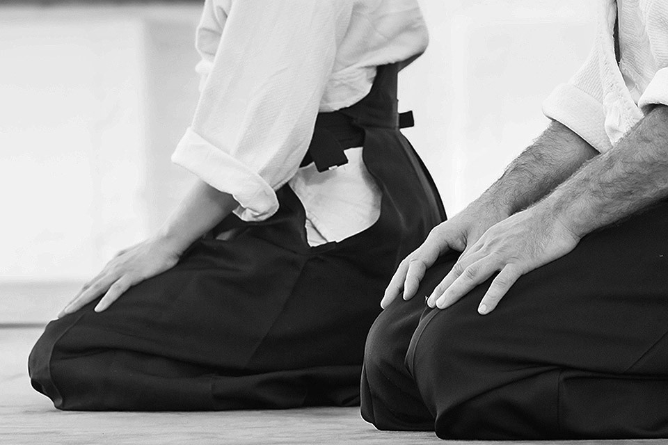 Students sitting with their hands on their knees, in the dojo
